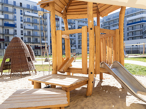 Auf unserem Sandspielplatz steht ein Rutschturm mit Dach, Plattformen auf verschiedenen Höhen und Vorrichtungen die zu Sandspielen einladen.
