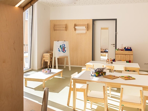 In unserem Atelier gibt es mehrere Tische in verschiedenen Höhen, eine Staffelei und Papierrollen an der Wand.