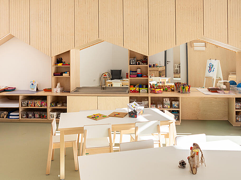 Unser Atelier. Ein heller Raum mit Tischen und vielen Kunstmaterialien.