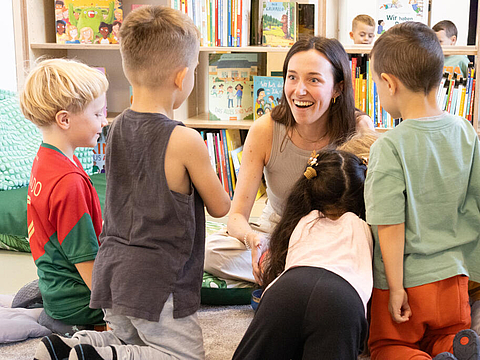 Eine pädagogische Fachkraft liest einer Kindergruppe vor